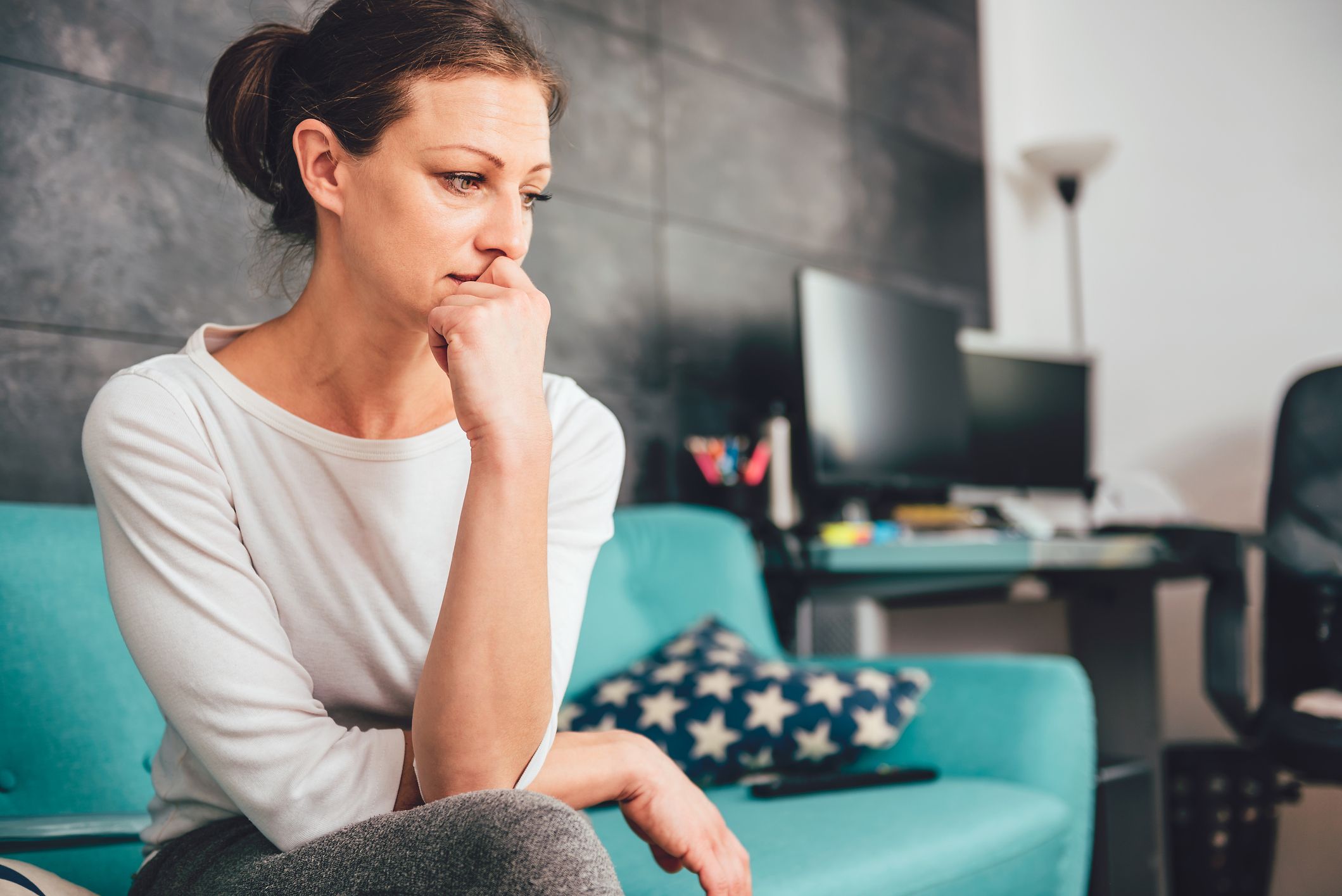 Nachdenkliche Frau auf Couch überlegt, ob sie eine Kinderwunschbehandlung machen lässt