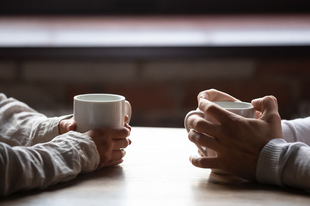 Zwei Personen halten Teetasse fest bei Beratung