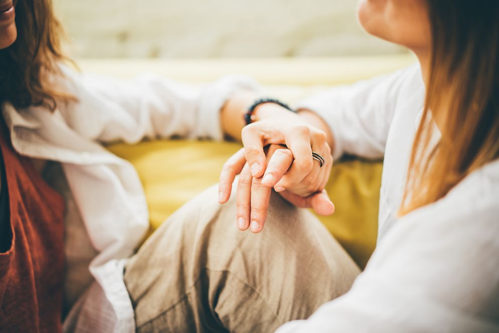 Zwei Frauen sitzen auf dem Boden und halten ihre Hände