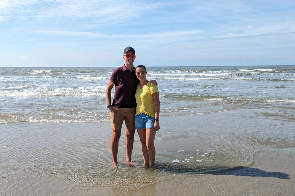 Ein junges Paar steht am Strand mit den Füßen im Wasser